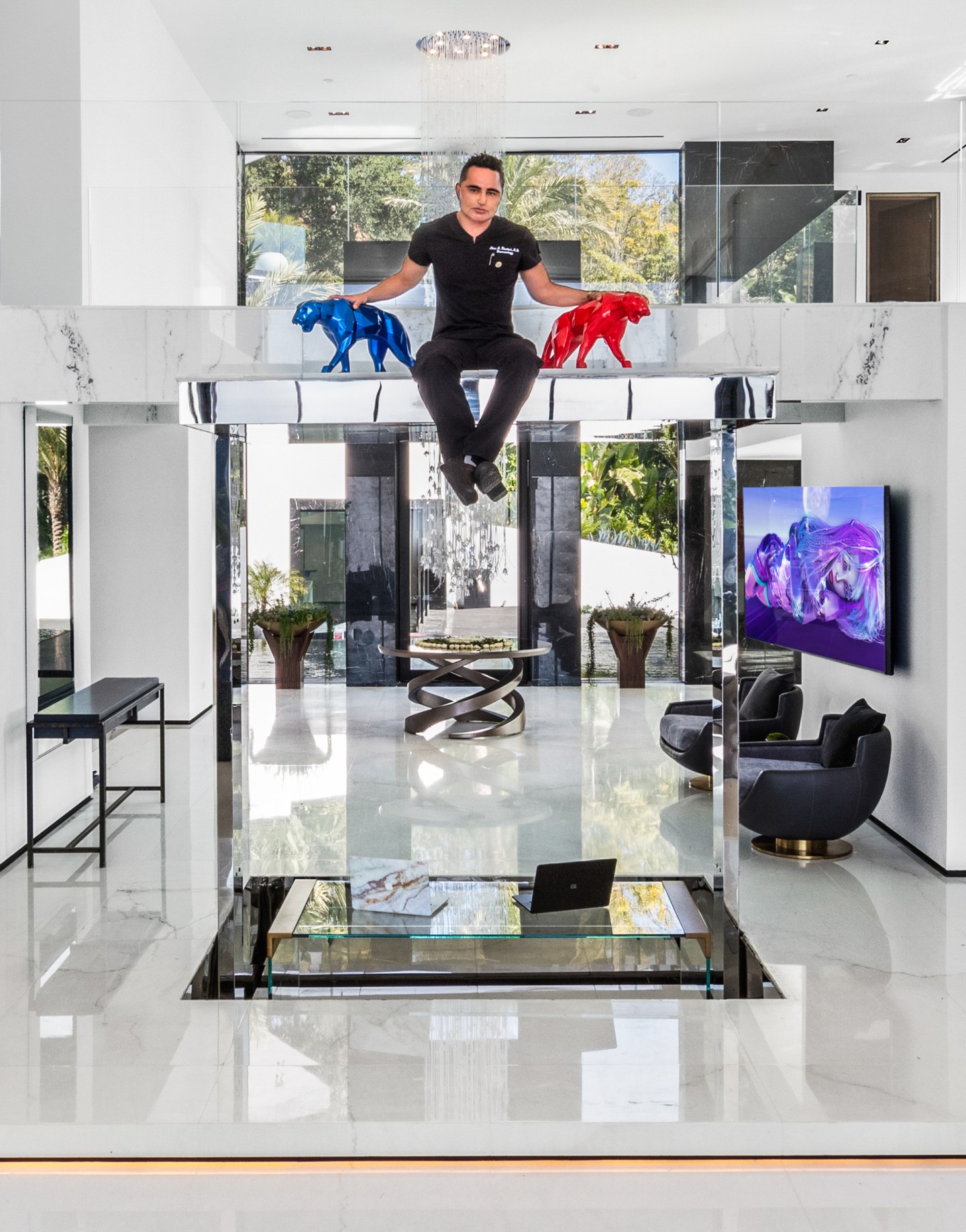 Dermatologist-turned-developer Alex Khadavi is pictured in the Bel Air mansion. He is seen sitting on the elevated DJ deck between two stone pumas, one red and one blue.