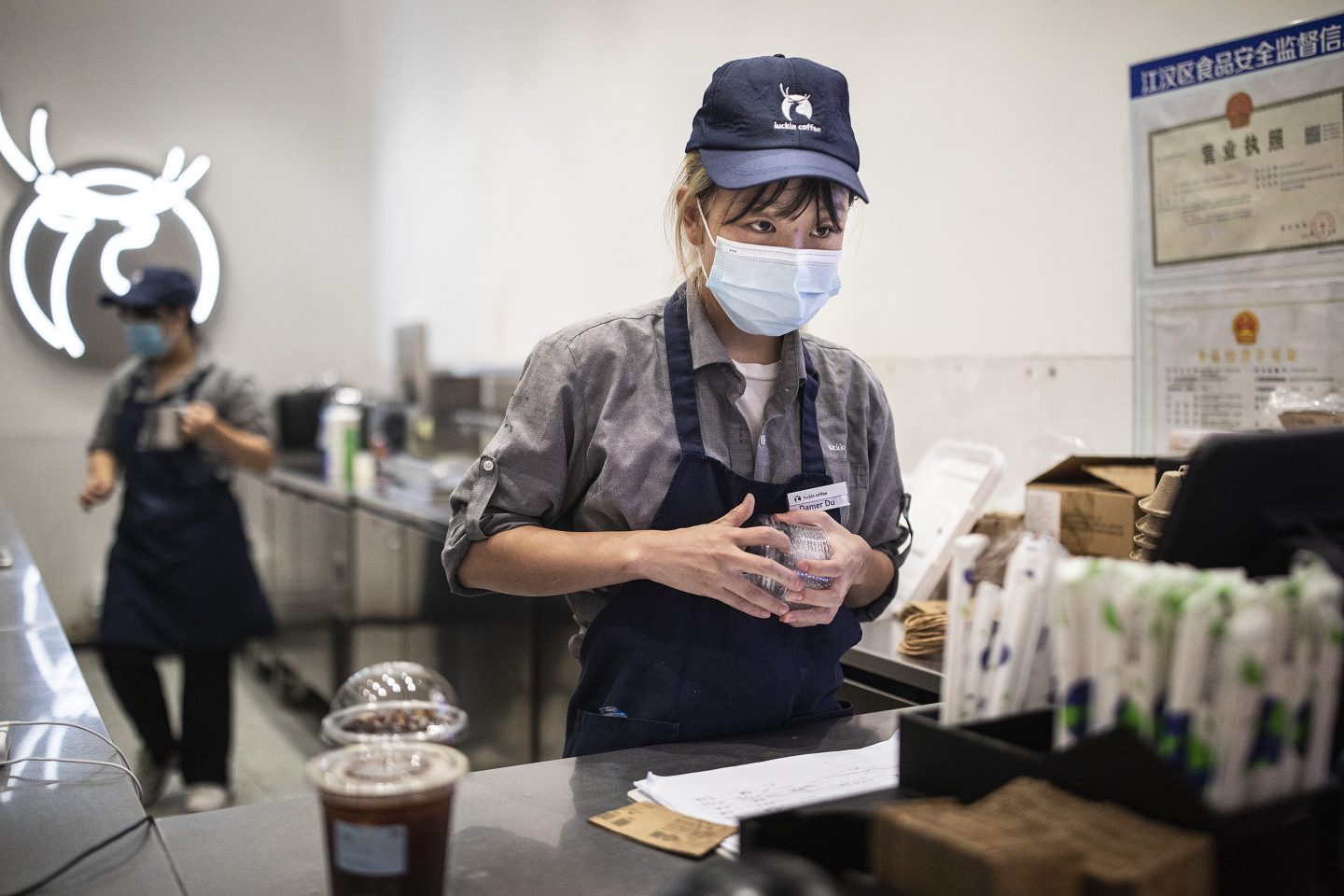 A Luckin Coffee employee inspecting a coffee cup lid