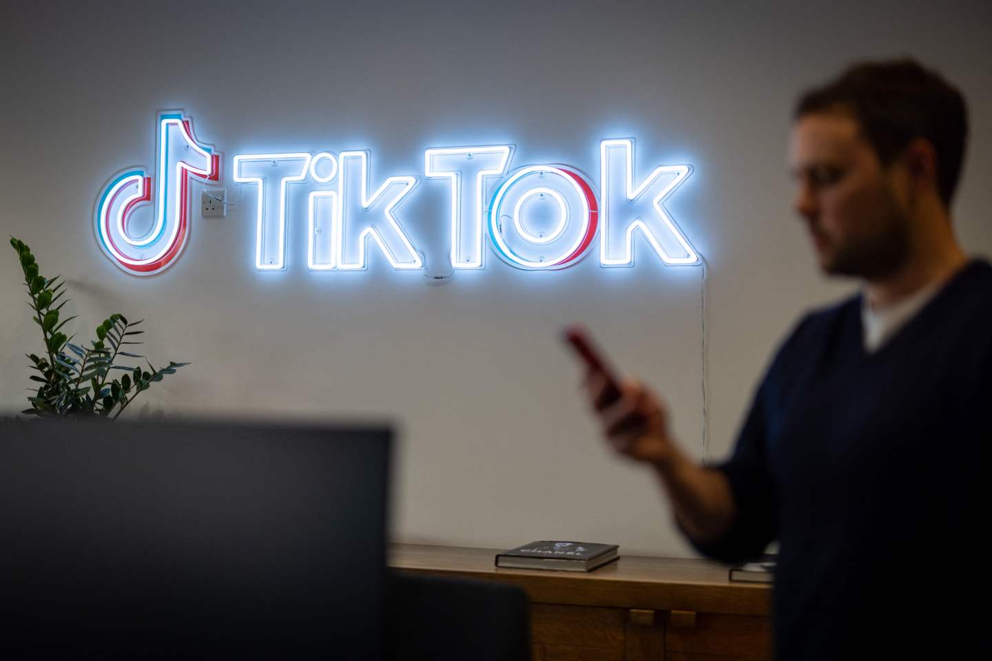 A man walks by a neon TikTok sign