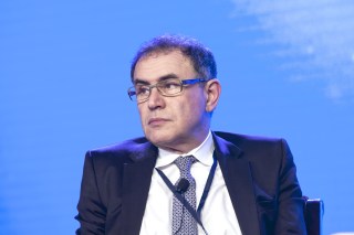 Shot of economist Nouriel Roubini sitting at a conference panel