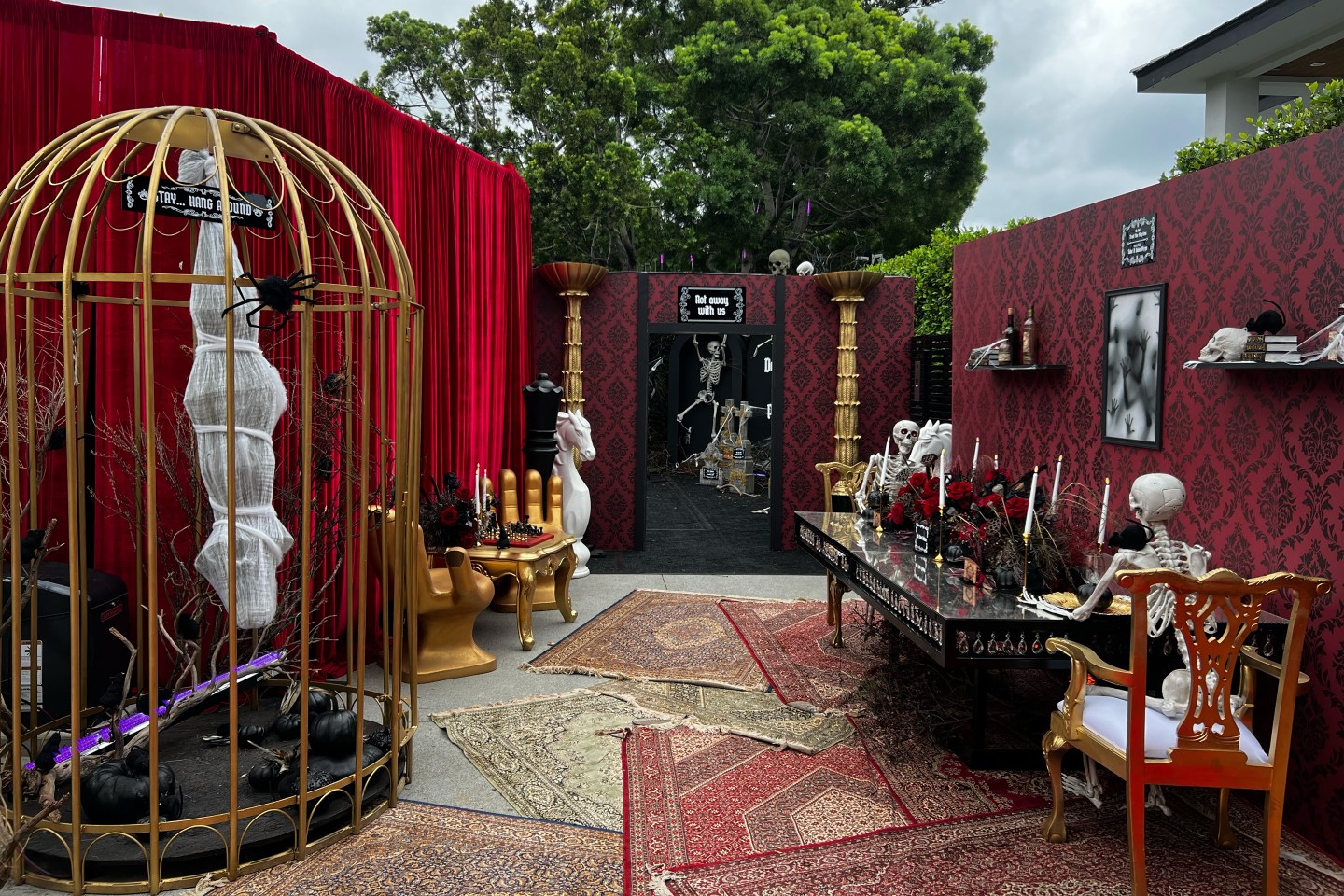 On the left, a mummy hanging from a cage. On the right, two skeletons at a table.
