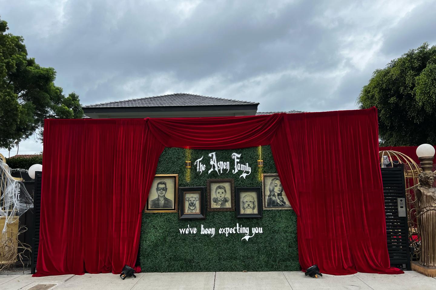 A Halloween display in front of a house that includes photos and a curtain.