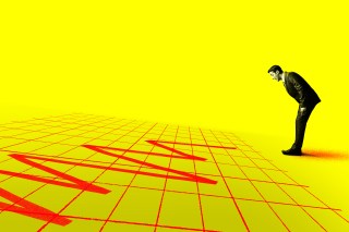 Photo illustration of a man in business attire leaning forward over a declining stock market chart and appearing stressed out.