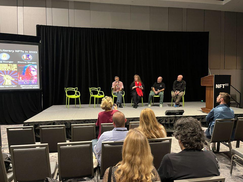 Speakers on the stage during a book-themed NFT event.