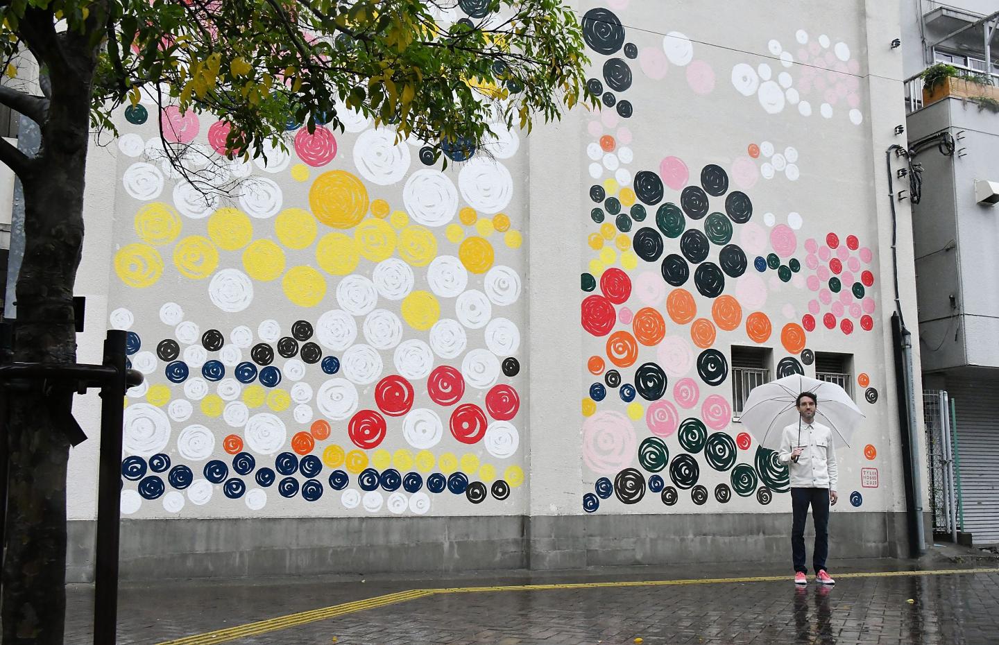 Tyler Hobbs poses for a photograph in front of his mural art wall on April 26, 2023, in Tokyo. 