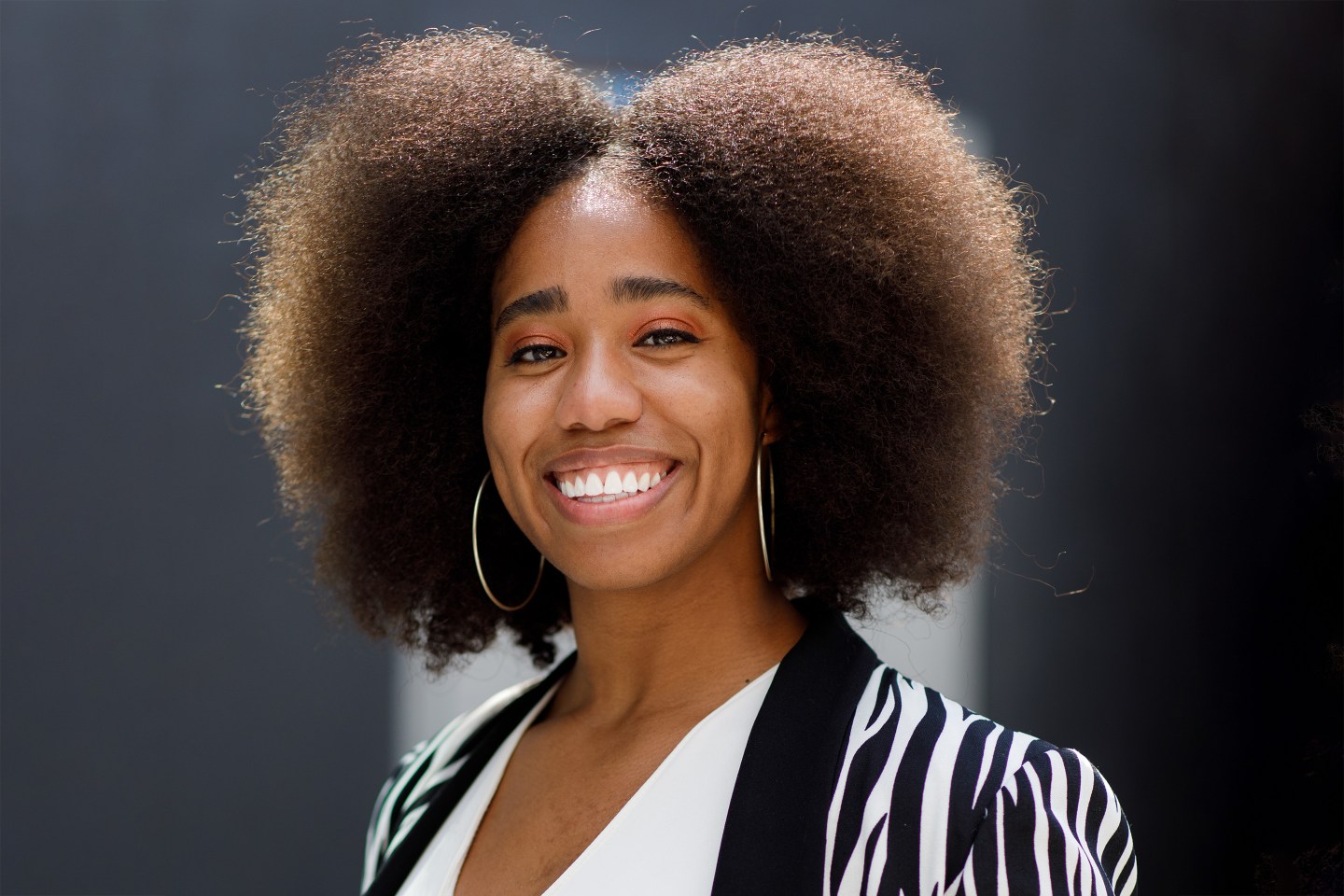 Amber Quiñones in animal print jacket smiling.