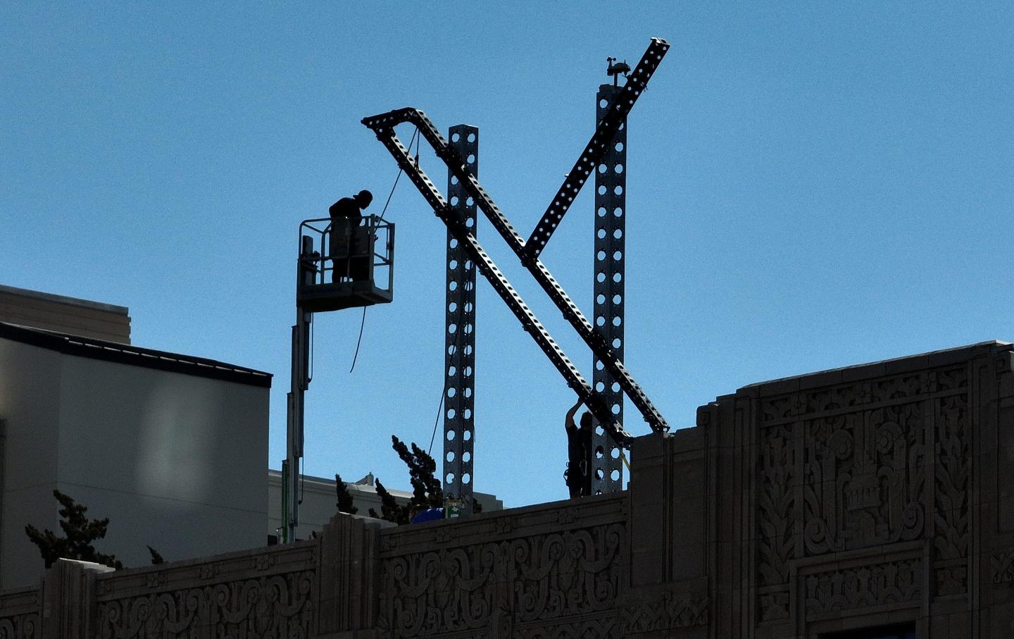Workers prepare to dismantle a large X logo on the roof of X headquarters on July 31, 2023, in San Francisco.