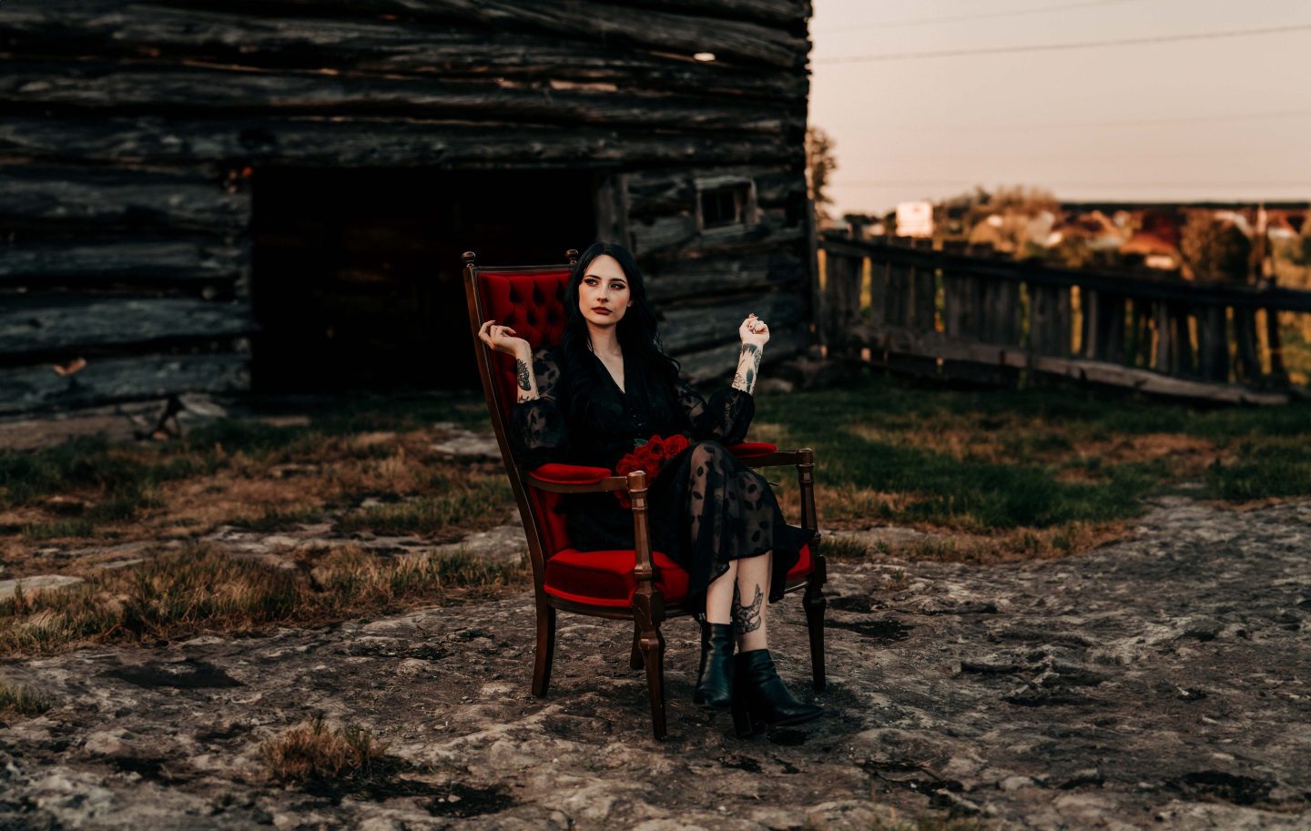 Chloe Hurst sitting in a red velvet chair wearing a black dress.