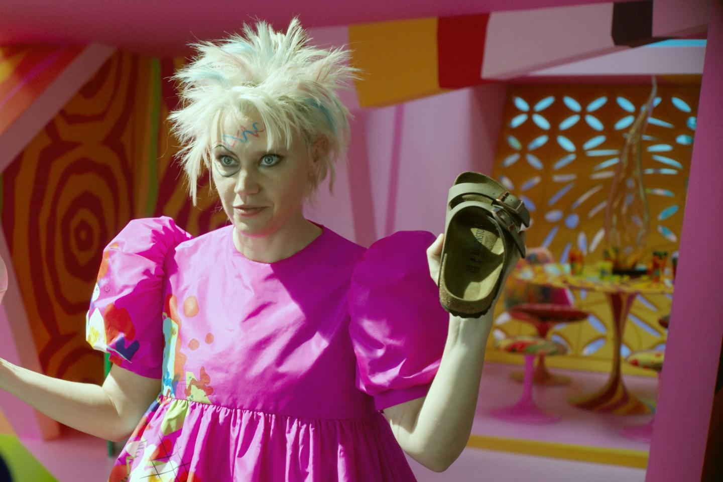 a scene of "weird barbie" holding a birkenstock sandal