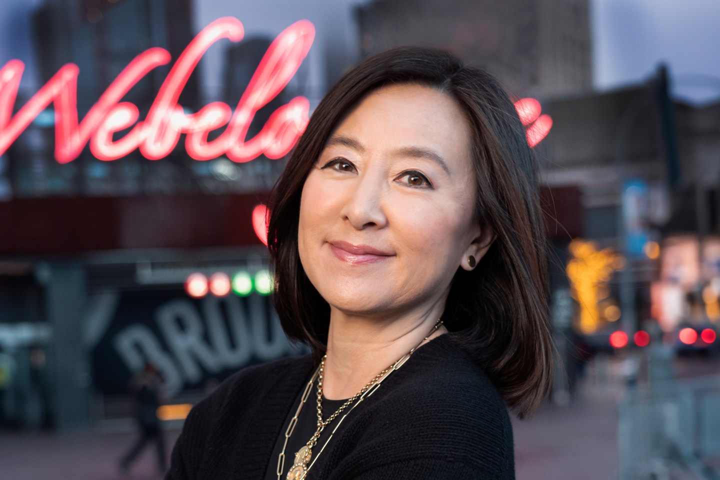 woman smiling in front of a street with neon lights