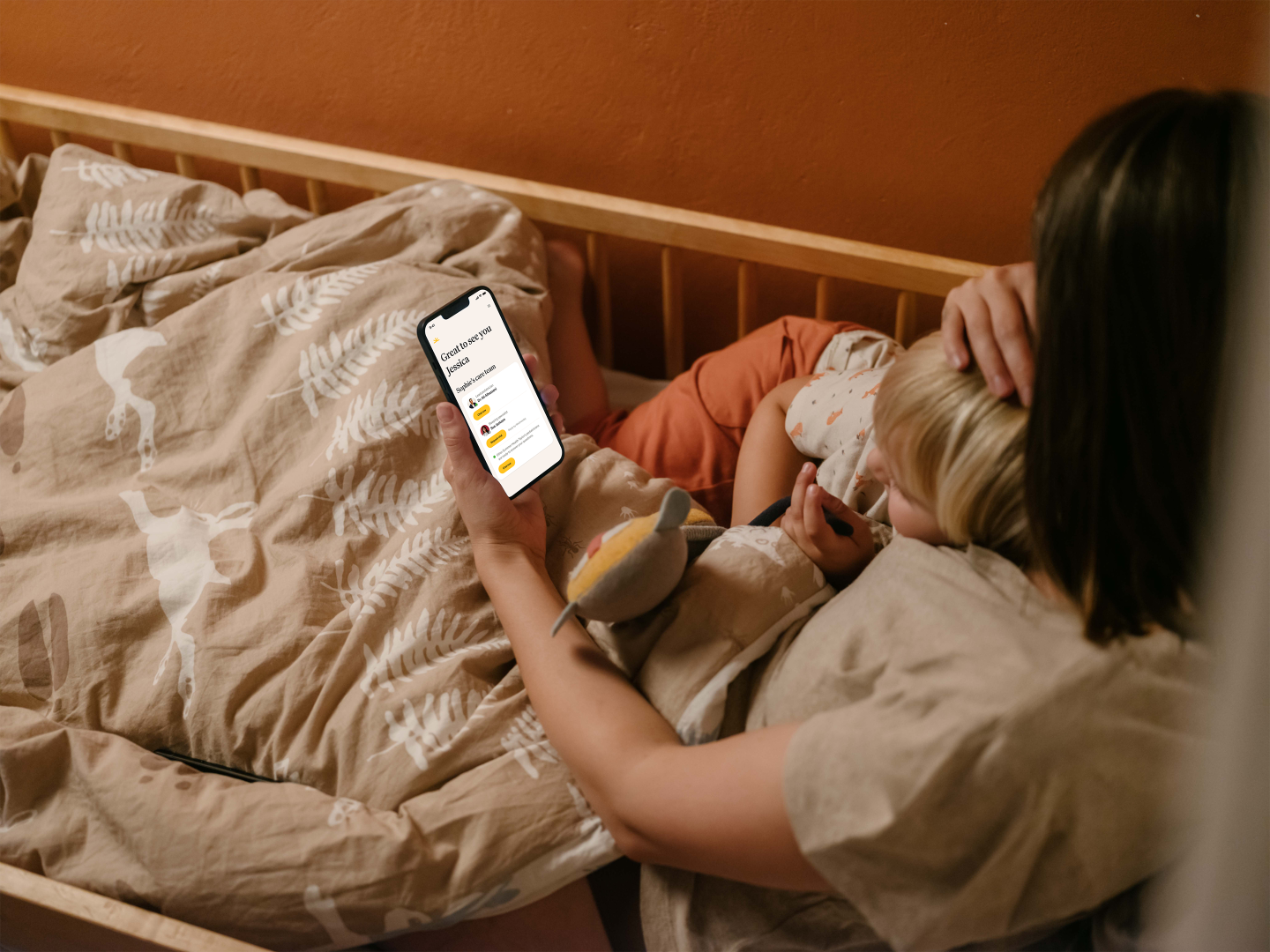 mom in bed with sick kid using her phone to connect with a doctor