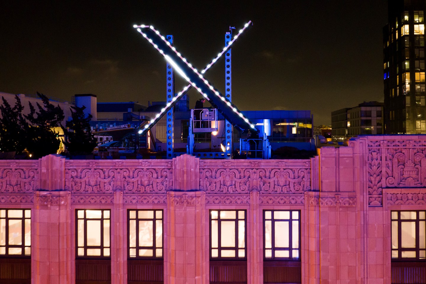 Workers install lighting on an "X" sign atop the company headquarters in San Francisco.
