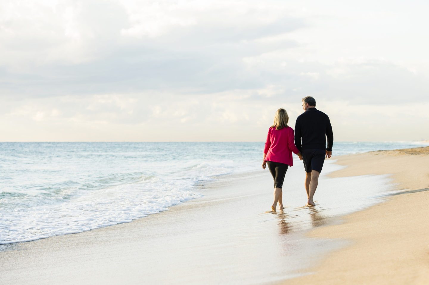 A man and a woman walking on a beach