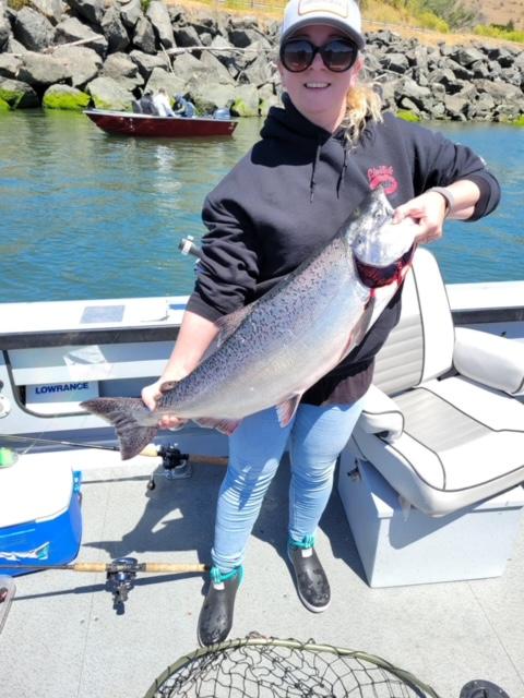 Woman standing on a dock holding a large fish