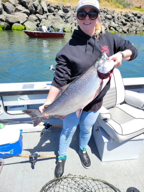 Woman standing on a dock holding a large fish