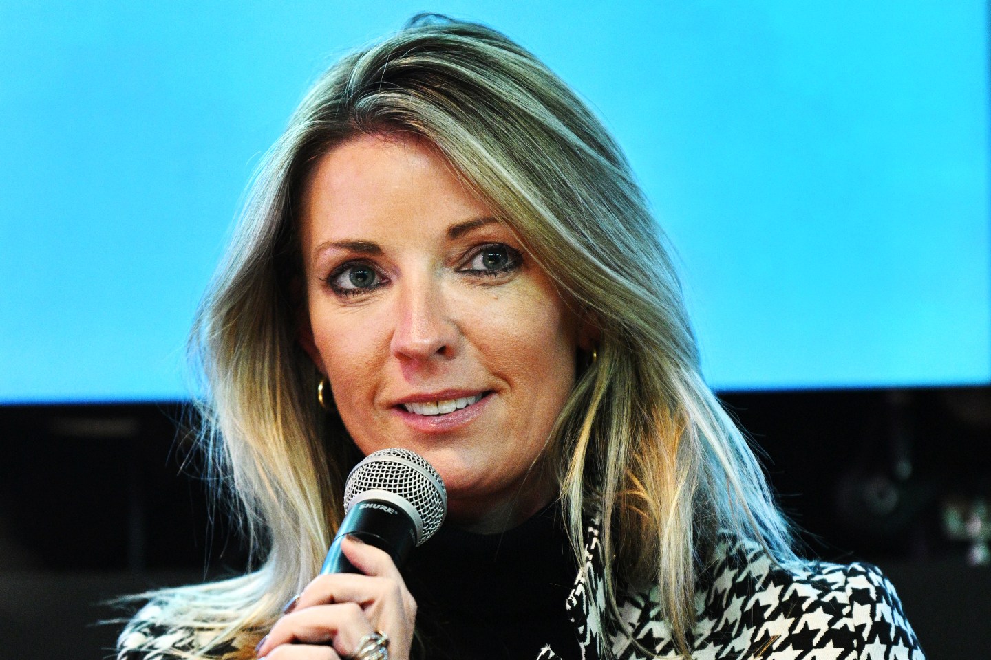 Natalie McGrath speaking into a microphone at a conference.